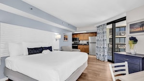 A modern hotel room with a large bed, a small kitchenette, and a balcony with a view. - Updated Oceanfront 16th floor w/ Amazing Views! (Myrtle Beach)