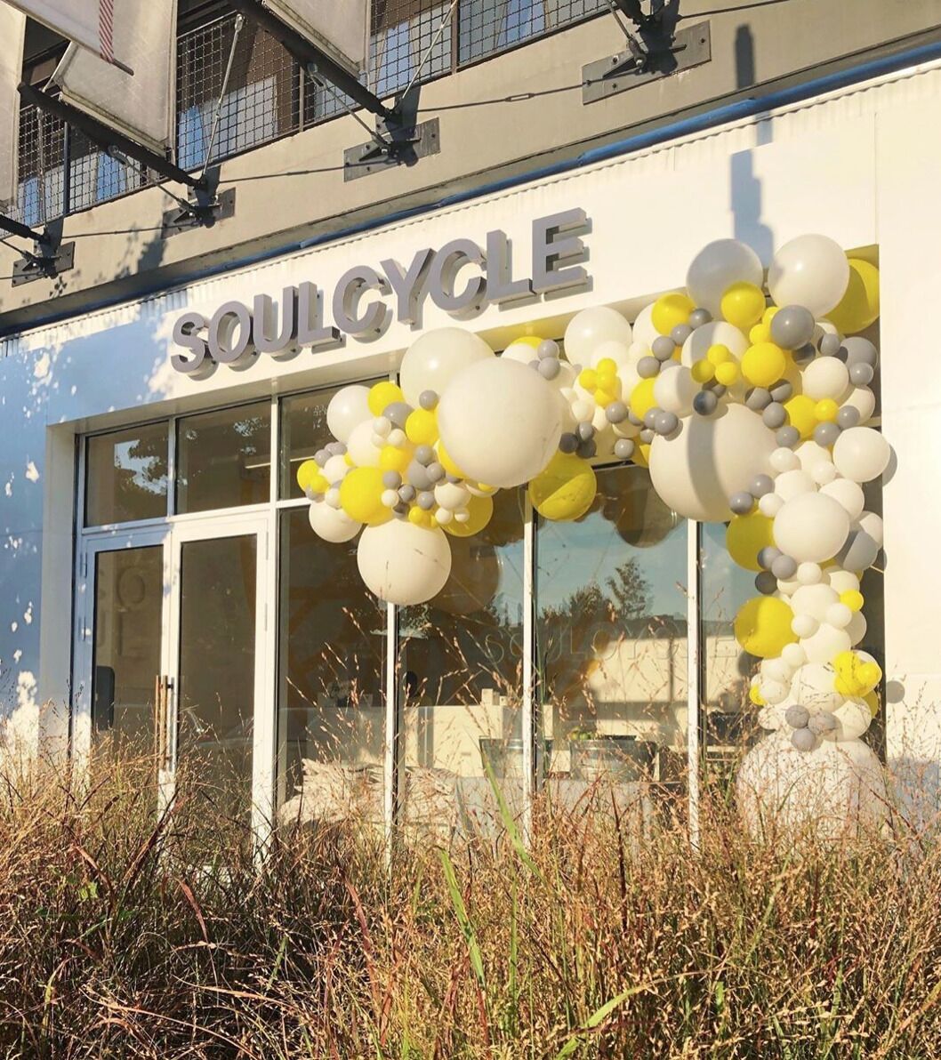 A storefront with the sign "SOULCYCLE" and a decorative balloon arrangement.