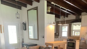 Uma sala de estar moderna com um sofá seccional, piso de madeira e uma área de cozinha ao fundo.