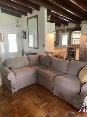Relax in this inviting living room with a large L-shaped sofa, dining table, and modern kitchen area.