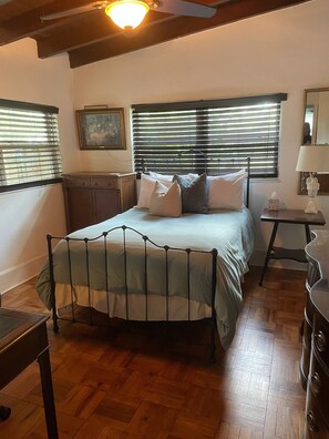 Cozy retreat with a metal-framed bed, ceiling fan, and a window with blinds.