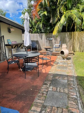Relax in a serene outdoor space with a round table, smaller table, and comfortable seating.