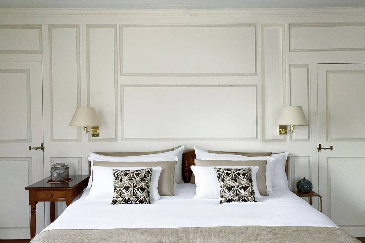 A hotel room with a large bed, two bedside tables, and two wall-mounted lamps.