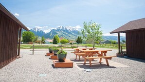 Un espace extérieur aménagé avec des tables de pique-nique et des jardinières, le tout sur fond de montagnes.