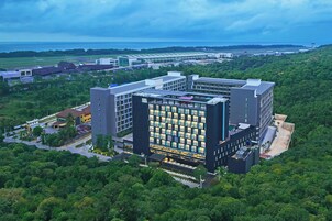 Un edificio moderno con fachada de vidrio, rodeado de exuberante vegetación.