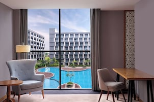Habitación de hotel con un ventanal grande, una piscina y dos sillas.
