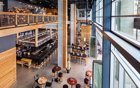 A spacious indoor area with multiple seating arrangements, a bar area with shelves, and large windows providing natural light.