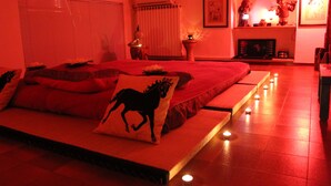 A bedroom with a bed, pillows, a nightstand, and a wall-mounted shelf with decorative items. - CLASSIC ROOM IN VILLA SPA (Mesagne)