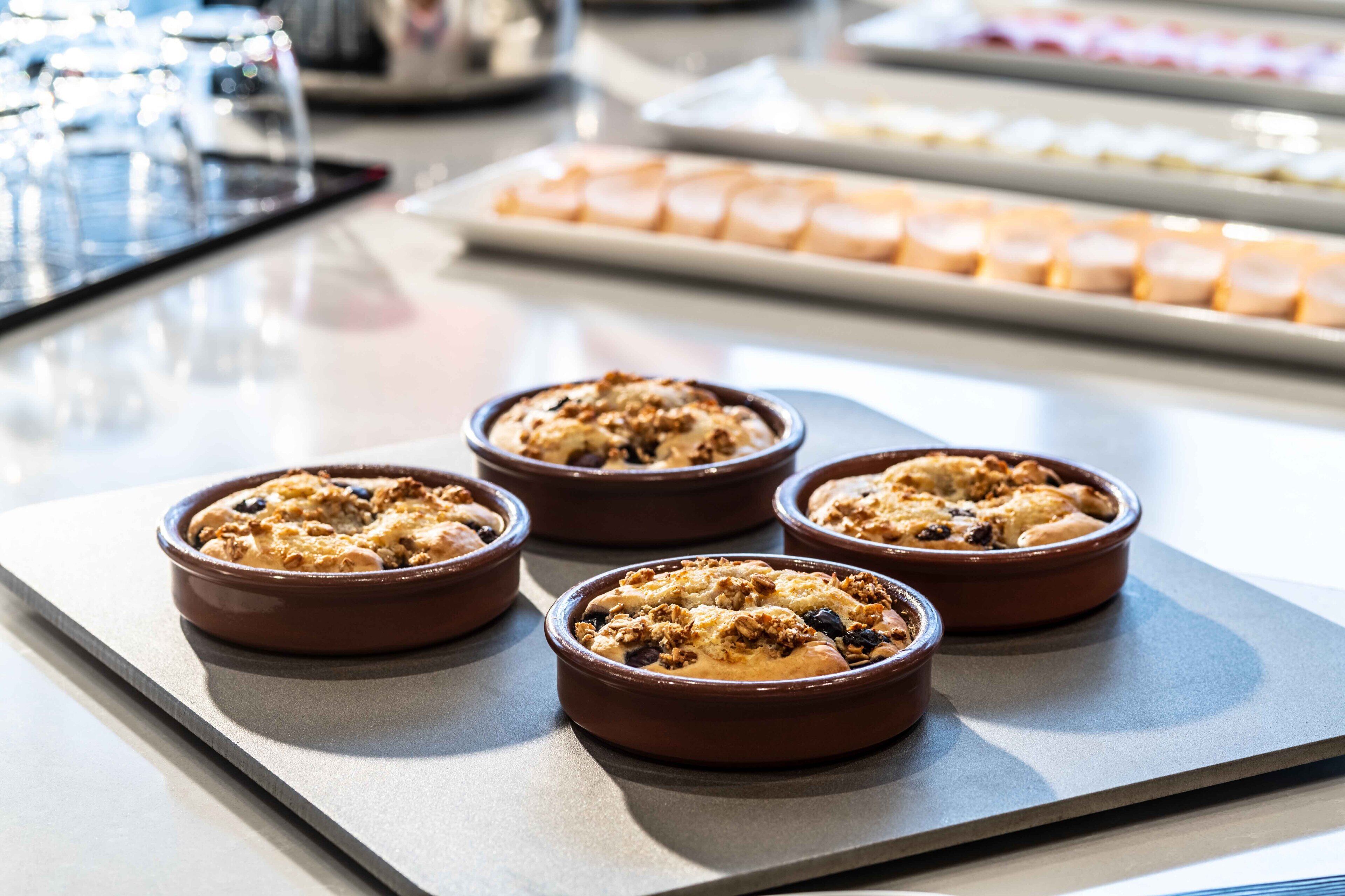 Four baked dishes in ceramic bowls on a countertop.