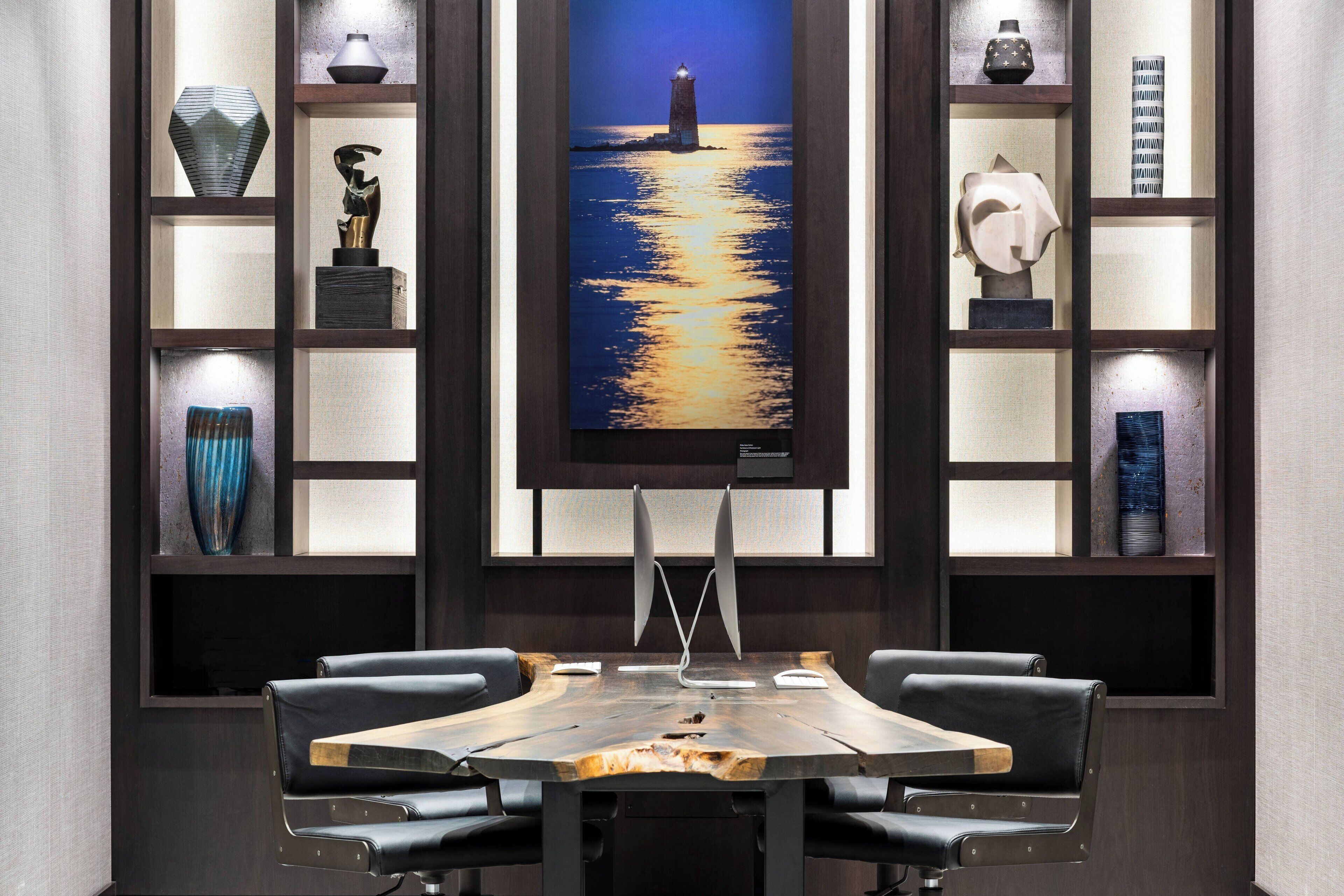 A conference room with a large painting of a lighthouse at sea, wooden tables, and modern chairs.