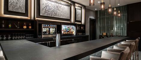 A modern bar area with a long counter, bar stools, and decorative wall art.