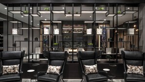 A modern interior with black leather chairs, a central fireplace, and shelves with plants and books. - AC Hotel by Marriott Portsmouth (Portsmouth)
