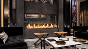 A modern interior with a fireplace, dark furniture, and a patterned rug. - AC Hotel by Marriott Portsmouth (Portsmouth)
