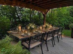 An outdoor dining area with a wooden pergola, tables set with candles, and chairs. - Hilltop Manor, A home for the Holidays. Sleeps 16 (Covington)