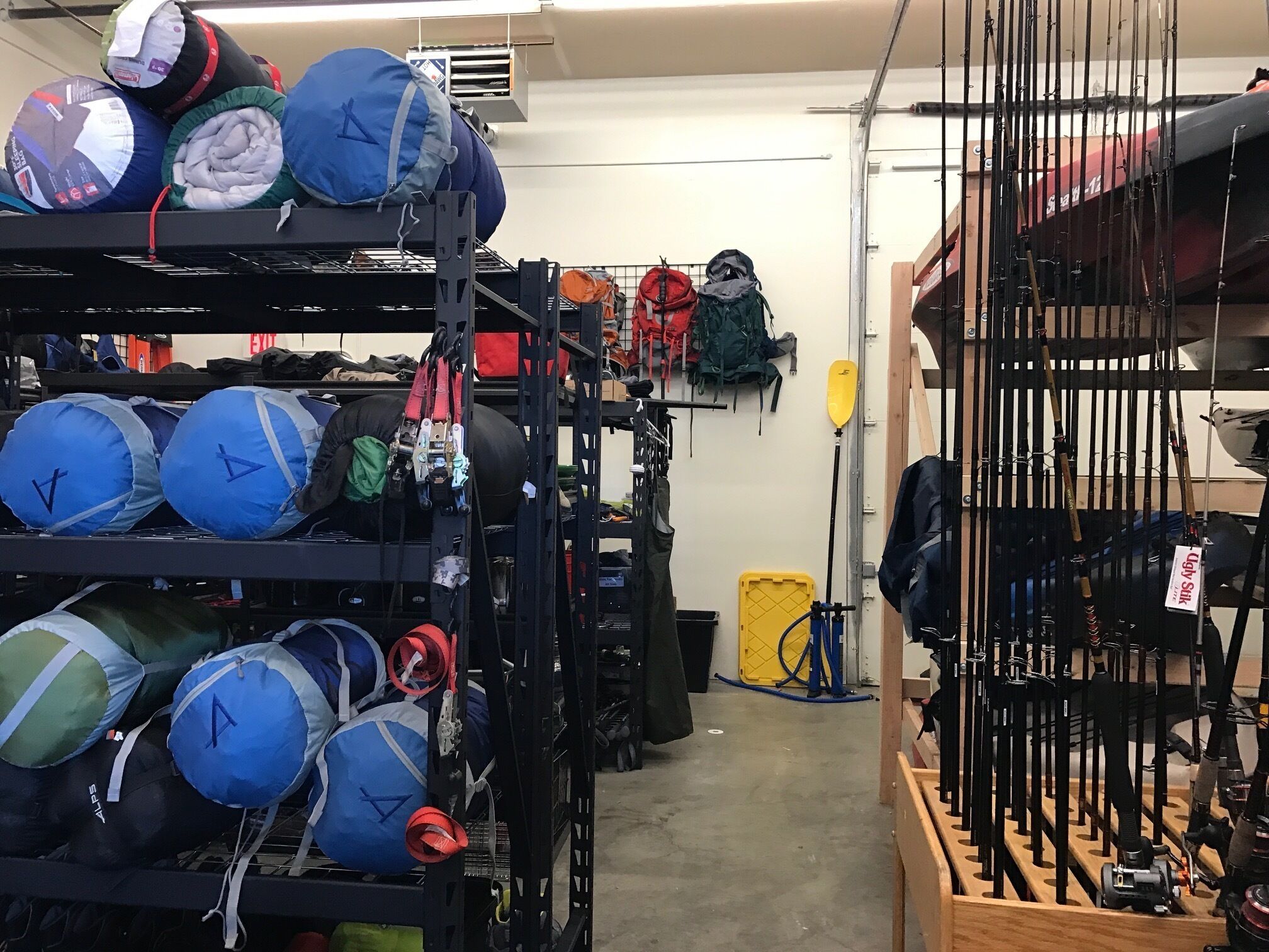 A storage room with shelves filled with various bags and equipment, including blue bags with handles and a yellow container.