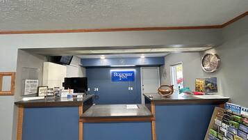 A reception desk with a sign reading "Rodeway Inn" and a clock on the wall.