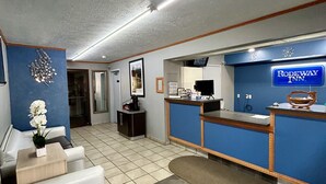 Zona de recepción de un hotel con un mostrador azul, una máquina de café y un letrero de Rodeway Inn.