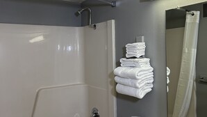 Un baño con bañera, inodoro, lavabo y una pila de toallas blancas.