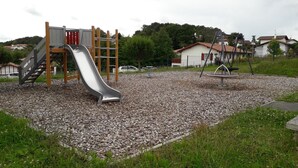 Une aire de jeux avec un toboggan, une structure d’escalade et des balançoires.