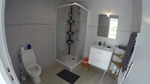 Une salle de bain moderne équipée de toilettes, d’une douche, d’un lavabo et d’un miroir.