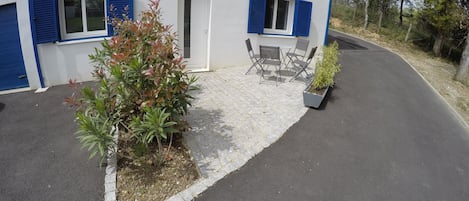 A building with blue shutters, a paved entrance, and outdoor seating.