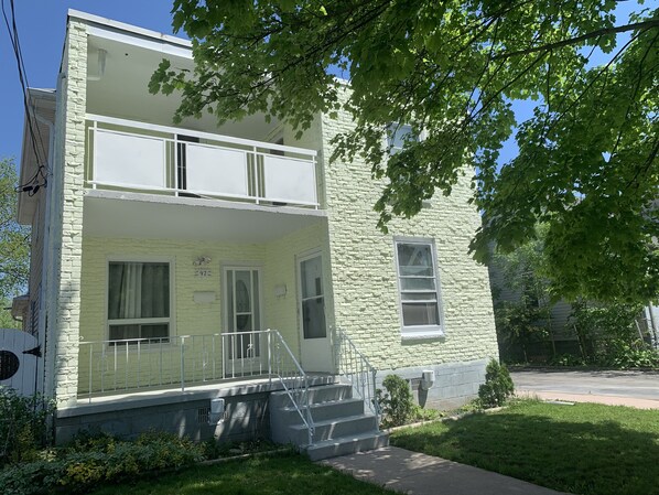A two-story building with a balcony, a visible number '972' on the door, and a small front yard. - Be At Home Away From Home (Welland)