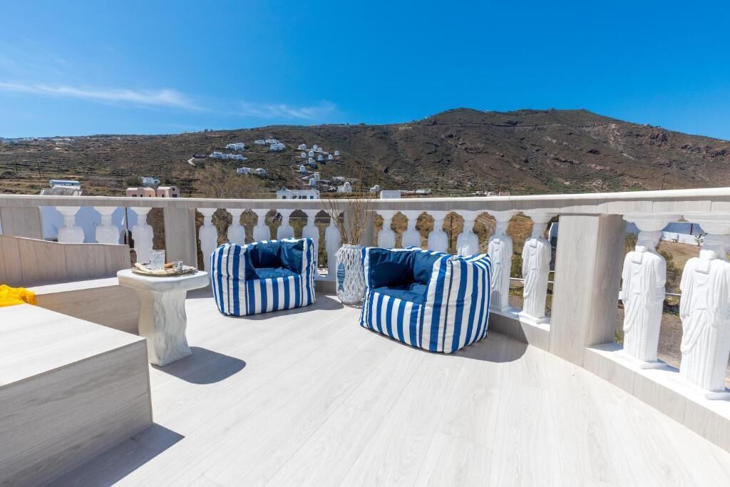 A terrace with two striped bean bags, a white table, and white statues.