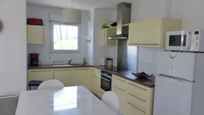 Una cocina moderna con una mesa blanca, armarios amarillos, un microondas y una estufa.