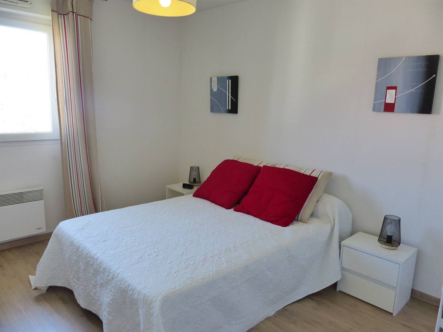 A bedroom with a bed, a nightstand, a lamp, and a wall-mounted artwork.