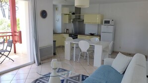 Una sala de estar moderna con un sofá azul, una mesa de centro de vidrio y una alfombra estampada.