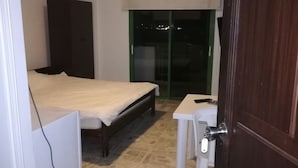 A bedroom with a bed, a desk, and a wardrobe.