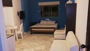 A room with a bed, a sofa, a small table, and a TV.