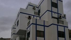 A modern building with a pool area, featuring a blue and white color scheme and a thatched roof structure.