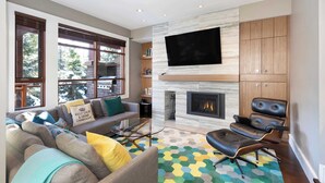 Una sala de estar moderna con chimenea, asientos cómodos y un televisor de pantalla plana grande.