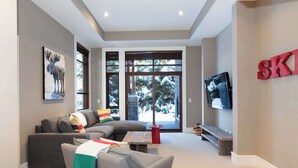 Una sala de estar moderna con un sofá modular, una mesa de centro y un televisor montado en la pared.