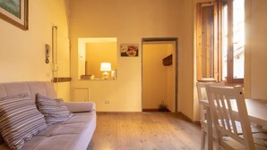 Una habitación acogedora con sofá, mesa de comedor, lámpara y espejo.