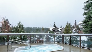 A hot tub on a balcony with a view of houses and trees.