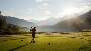 A golf course with a person playing, surrounded by mountains and a lake. - Whistler retreat w/ private hot tub & ski access (Whistler)