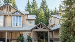 A two-story house with a stone facade, large windows, and a covered porch. - Whistler retreat w/ private hot tub & ski access (Whistler)