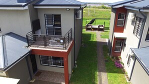 A multi-story building with a balcony, a sign indicating it is a hotel, and a view of a grassy area with a barbecue setup. - Mi Gran Amor Termas (San José)