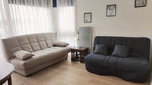 A living room with a beige sofa, a dark grey sofa, and a small wooden table. - CAP SUD residence- Flat for 3 persons close to marina (CAPBRETON)