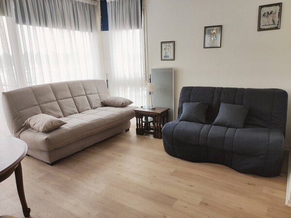A living room with a beige sofa, a dark grey sofa, and a small wooden table.