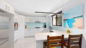 Una cucina moderna con mobili bianchi, una grande isola centrale e un'area pranzo con sedie di legno.