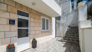 Un moderno edificio residenziale con facciata in pietra, una porta in vetro e una scala che conduce a un piano superiore.