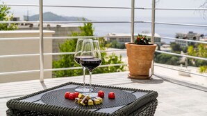 Un balcone con un tavolino in vimini, due bicchieri da vino e una pianta in vaso.