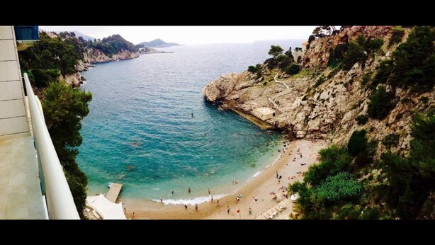 Vista sulla costa con spiaggia, scogliere rocciose e mare cristallino.