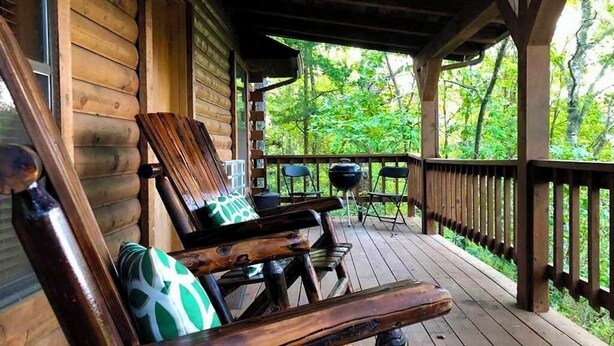 A wooden deck with outdoor seating and a grill. - Tranquil Cabin- Perched on Mountain Top boasting jacuzzi for two and expansive deck with views! Trail & Cave on Property! (Eureka Springs)