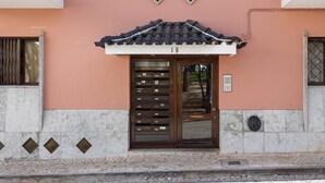 Un bâtiment doté d’un toit traditionnel recouvert de tuiles, d’une porte portant un numéro et d’un petit balcon agrémenté d’une rambarde en métal.