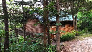 A log cabin with a wooden deck and a metal railing. - Tranquil Cabin- Perched on Mountain Top boasting jacuzzi for two and expansive deck with views! Trail & Cave on Property! (Eureka Springs)