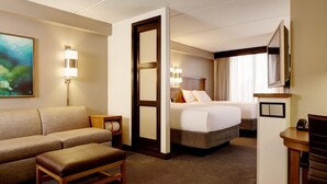 Een hotelkamer met een bank, een bed, een bureau en een televisie.